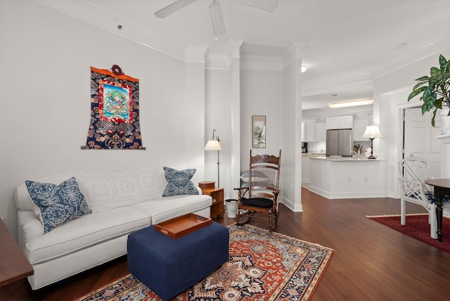 living room with ornamental molding, dark wood-type flooring, and ceiling fan