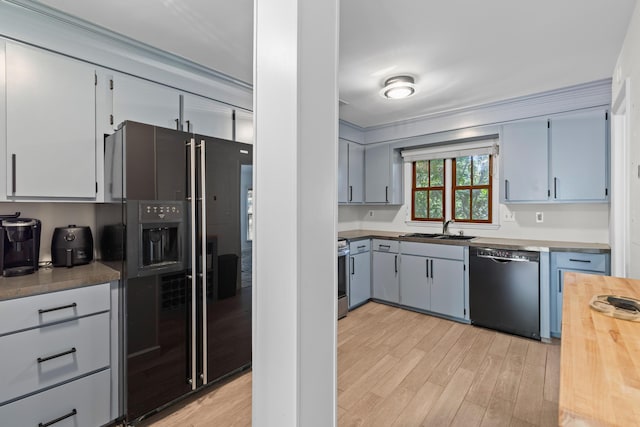 kitchen featuring light wood-type flooring, wooden counters, a sink, and black appliances