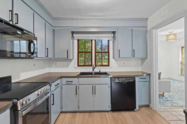 kitchen featuring light wood-style floors, a sink, black appliances, and dark countertops