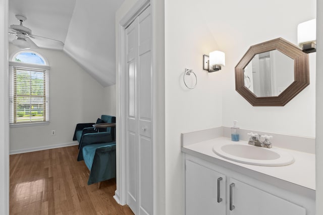 bathroom with baseboards, a ceiling fan, vanity, wood finished floors, and lofted ceiling