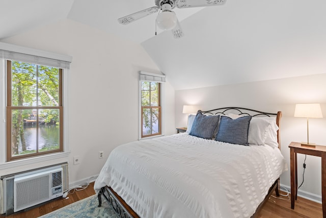 bedroom featuring wood finished floors, an AC wall unit, and lofted ceiling