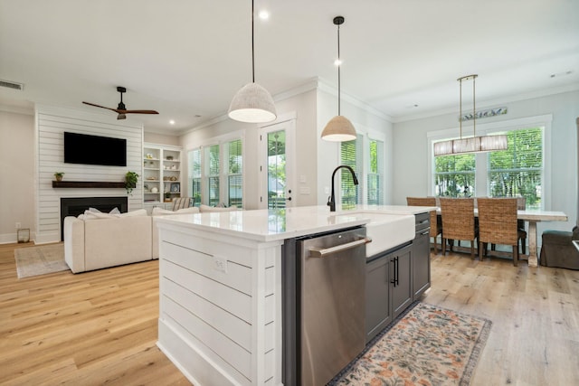 kitchen featuring a fireplace, a sink, light wood-style floors, ornamental molding, and stainless steel dishwasher