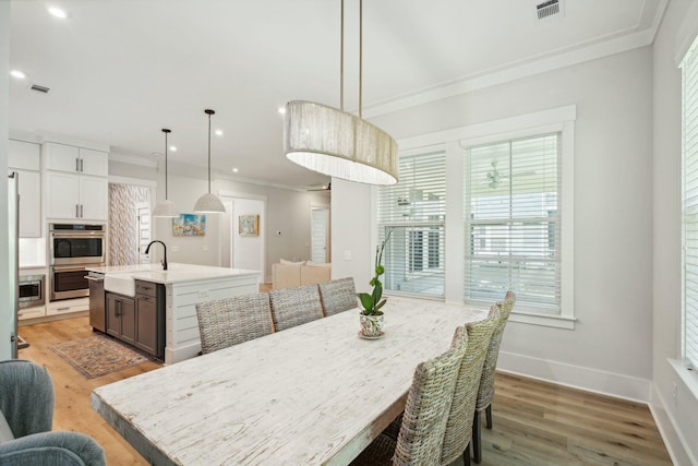 dining space with ornamental molding, visible vents, light wood-style flooring, and baseboards