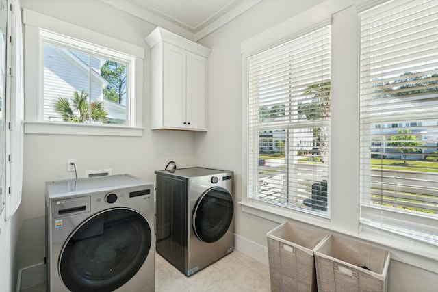 laundry area featuring cabinet space, light tile patterned floors, baseboards, and washing machine and clothes dryer