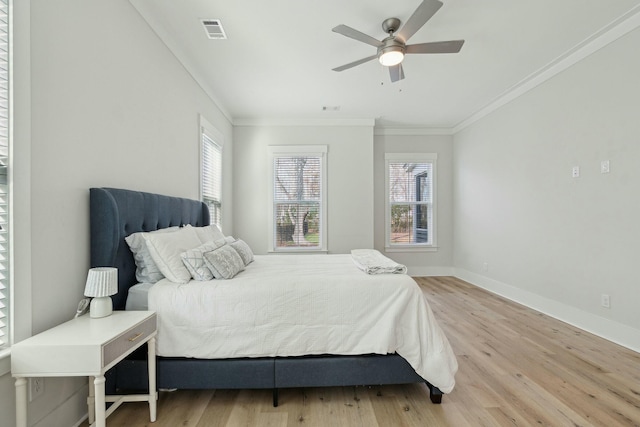 bedroom with baseboards, crown molding, visible vents, and wood finished floors