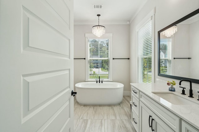 bathroom with vanity, visible vents, a freestanding bath, ornamental molding, and an inviting chandelier