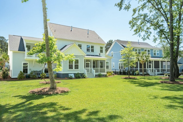 rear view of house featuring a yard, board and batten siding, fence, and a sunroom