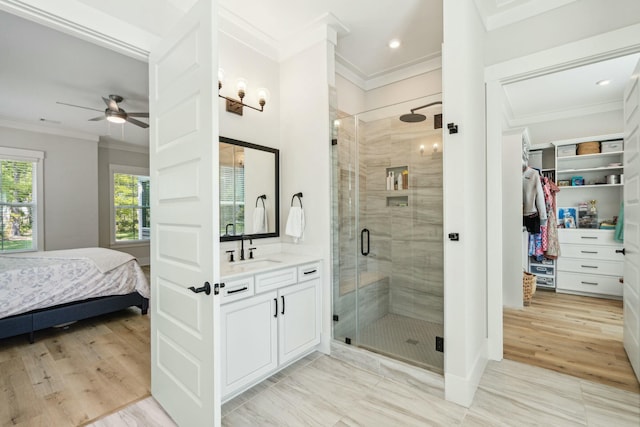 bathroom featuring a spacious closet, ornamental molding, a shower stall, vanity, and wood finished floors