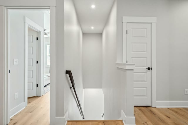 corridor featuring recessed lighting, light wood-type flooring, an upstairs landing, and baseboards