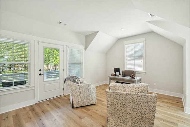 sitting room with lofted ceiling, light wood-style flooring, visible vents, and baseboards