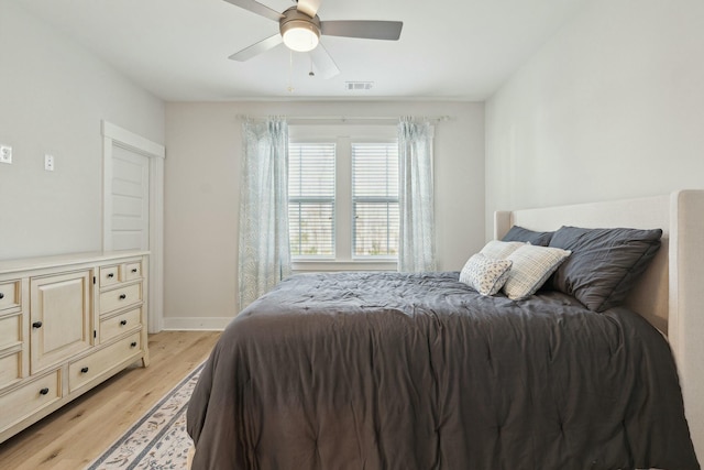 bedroom featuring ceiling fan, light wood-style flooring, visible vents, and baseboards