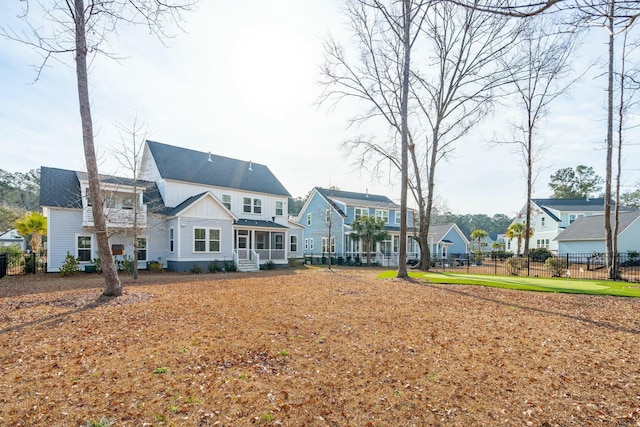 back of property with board and batten siding, a residential view, fence, and a lawn