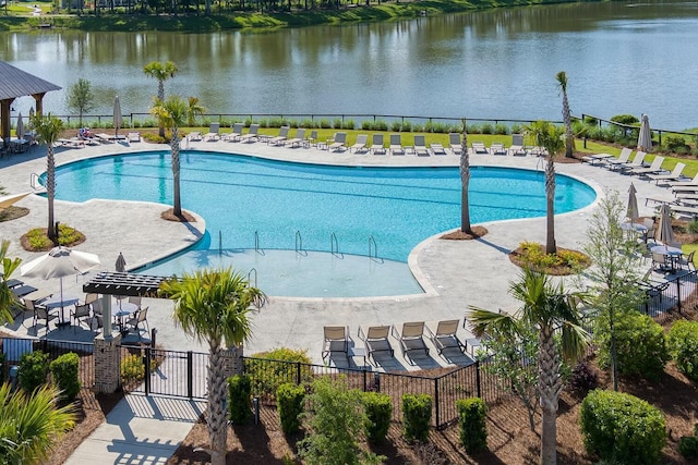 community pool with a patio, a water view, and fence