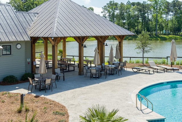 view of property's community featuring outdoor dining space, a patio area, a pool, and a water view