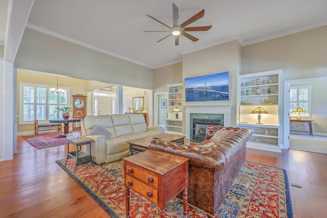 living room featuring crown molding, ceiling fan with notable chandelier, a fireplace, and hardwood / wood-style flooring