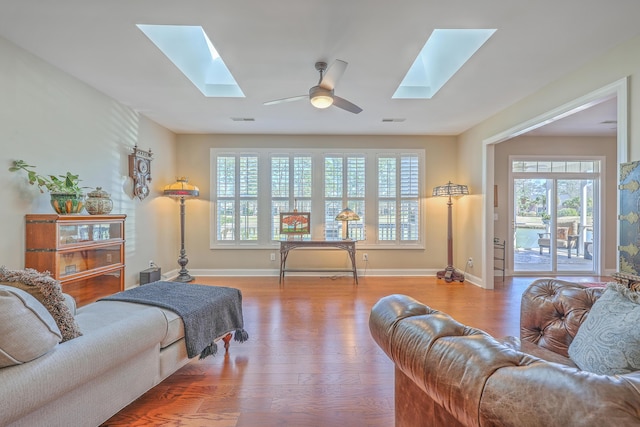 living room with a skylight, wood finished floors, and visible vents