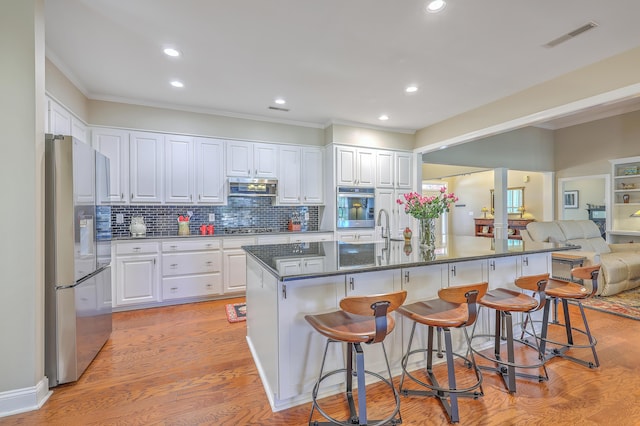 kitchen featuring light wood-type flooring, visible vents, stainless steel appliances, and exhaust hood