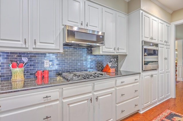 kitchen with stainless steel appliances, white cabinetry, light wood-style floors, backsplash, and crown molding