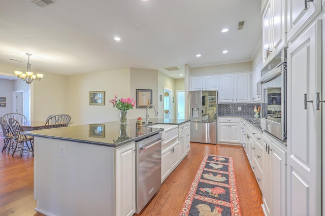 kitchen featuring light wood-type flooring, white cabinets, stainless steel appliances, and a sink