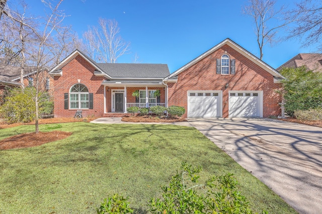 view of front of home featuring driveway, a garage, brick siding, covered porch, and a front yard