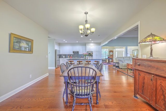 dining area with light wood-style floors, recessed lighting, a chandelier, and baseboards