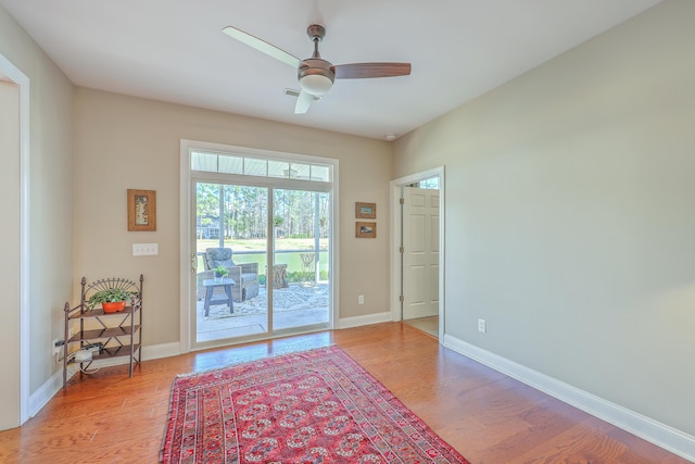 doorway featuring ceiling fan, light wood-style flooring, and baseboards