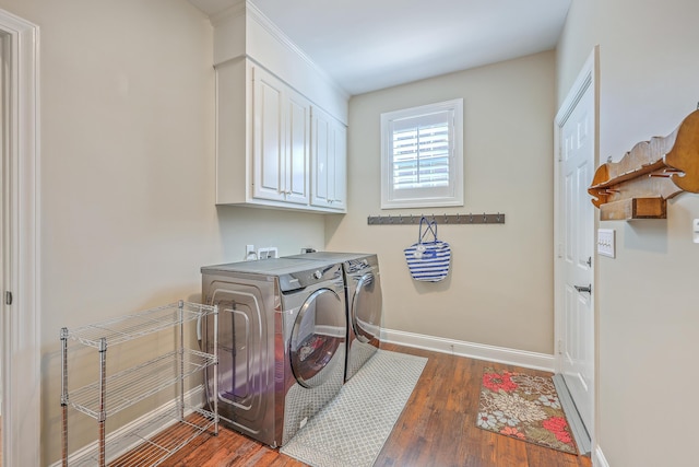 washroom featuring washer and dryer, cabinet space, baseboards, and wood finished floors