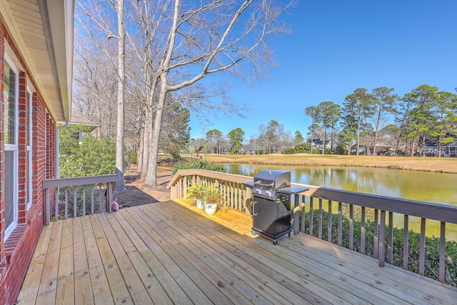 wooden deck featuring a water view and a grill