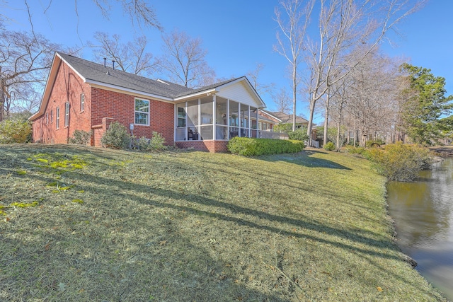 exterior space with a sunroom, a lawn, and brick siding