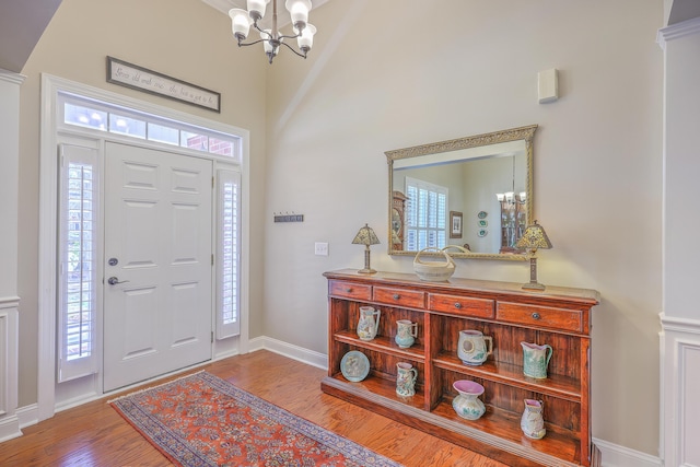 foyer featuring a healthy amount of sunlight, an inviting chandelier, baseboards, and wood finished floors