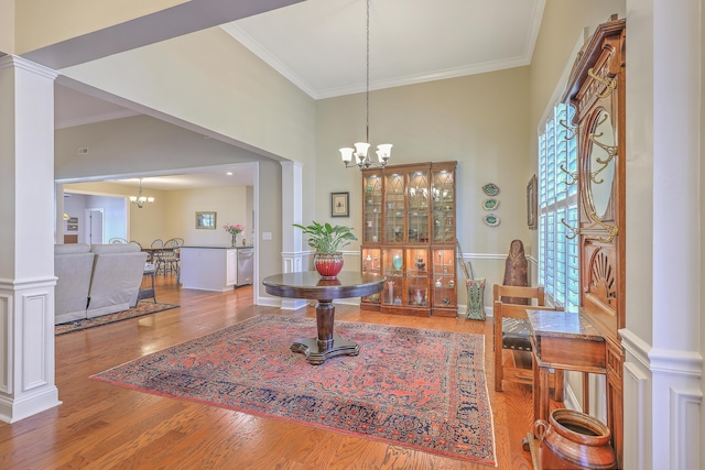 dining space with a chandelier, crown molding, wood finished floors, and ornate columns