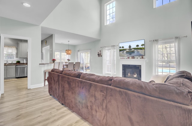 living room with baseboards, a glass covered fireplace, and light wood-style floors