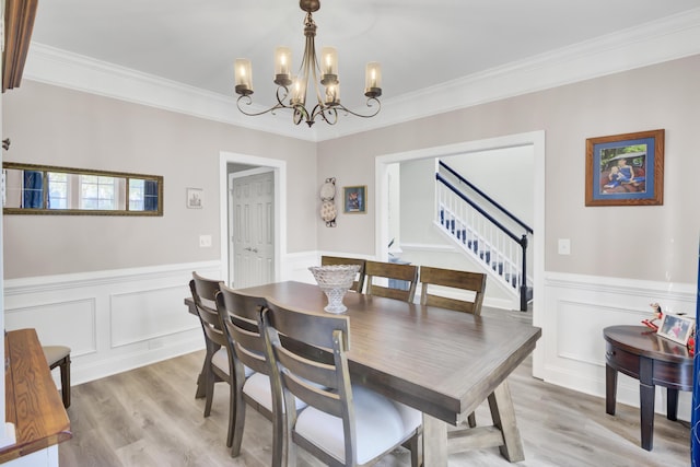 dining area featuring light wood-style floors, wainscoting, stairway, and an inviting chandelier