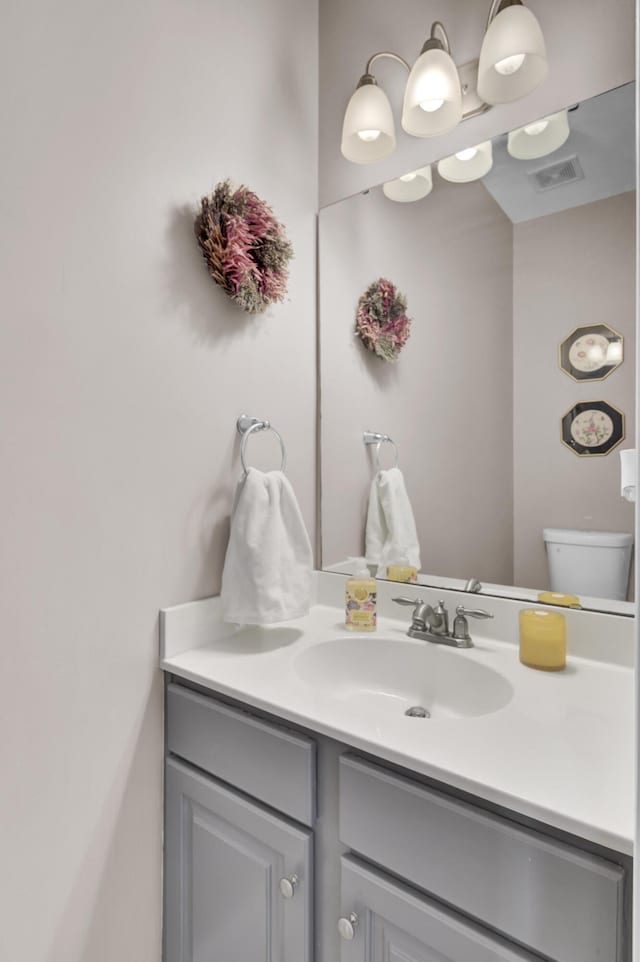 bathroom with toilet, visible vents, and vanity