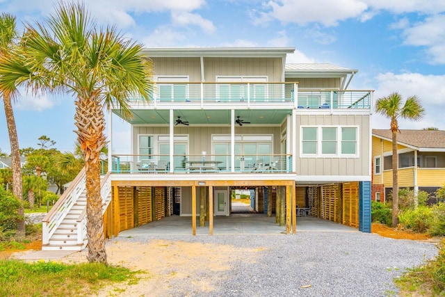 view of front of house featuring a ceiling fan, board and batten siding, a balcony, driveway, and stairs