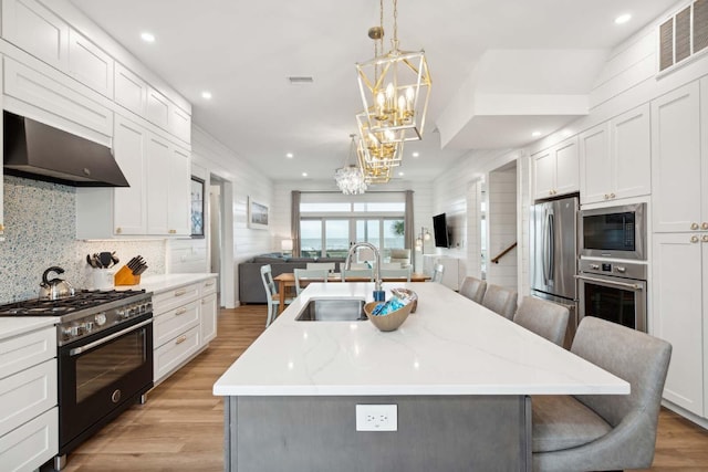 kitchen featuring visible vents, an inviting chandelier, stainless steel appliances, under cabinet range hood, and a sink