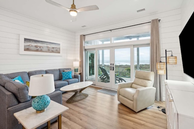 living room featuring a ceiling fan, french doors, visible vents, and light wood finished floors