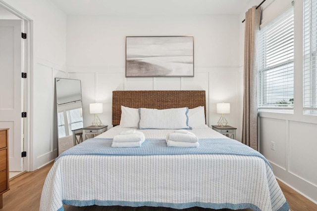 bedroom with a decorative wall and wood finished floors