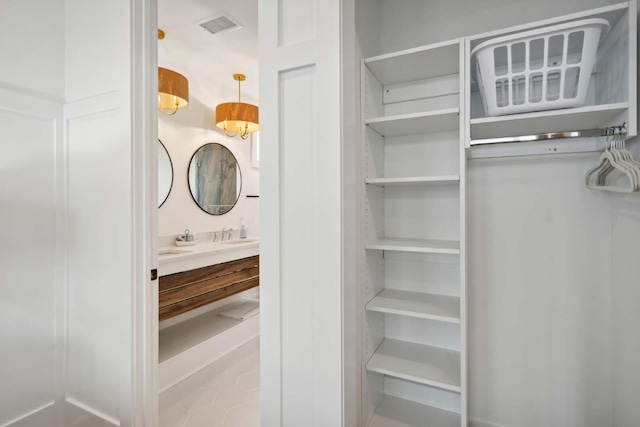 interior space featuring visible vents, vanity, and a spacious closet