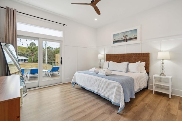 bedroom featuring access to exterior, a decorative wall, and wood finished floors