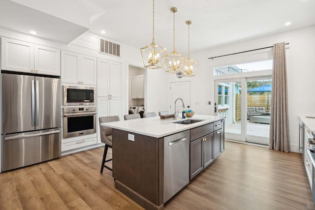 kitchen featuring a sink, visible vents, light wood-style floors, light countertops, and appliances with stainless steel finishes