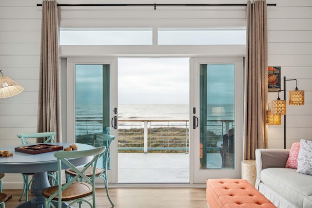 doorway with a water view, wood finished floors, and wooden walls