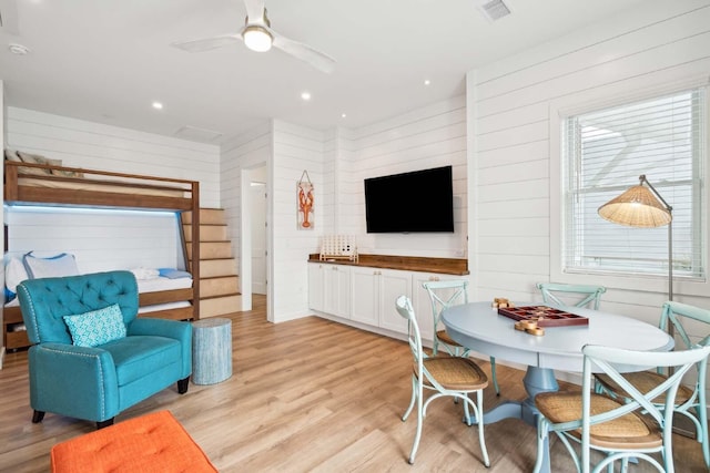 living room with visible vents, a ceiling fan, light wood-style flooring, wood walls, and recessed lighting