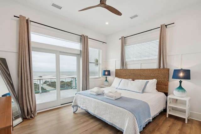 bedroom featuring access to outside, visible vents, a decorative wall, and wood finished floors