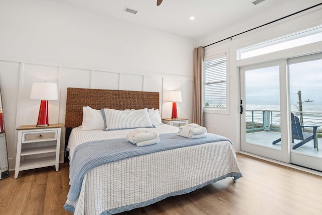 bedroom featuring access to outside, multiple windows, visible vents, and wood finished floors