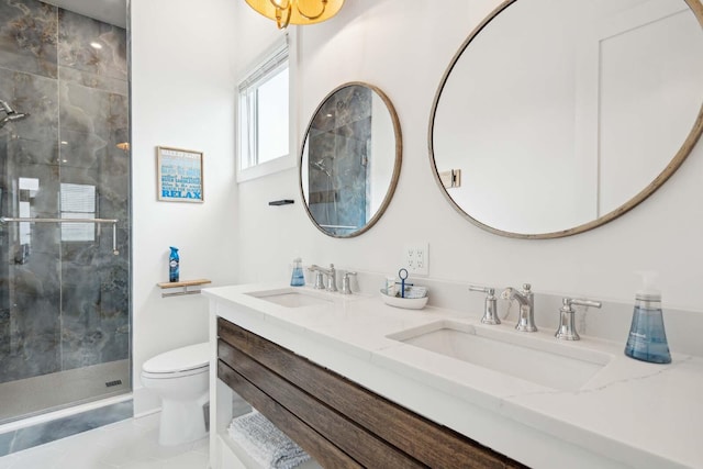 bathroom featuring toilet, a stall shower, double vanity, and a sink