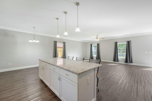 kitchen with a center island, ceiling fan with notable chandelier, ornamental molding, and dark wood-style floors