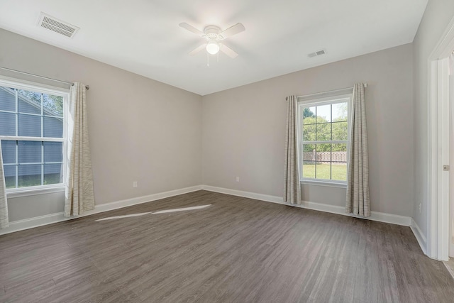 unfurnished room with visible vents, a wealth of natural light, and dark wood-style floors