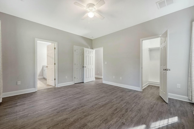unfurnished bedroom with dark wood-type flooring, baseboards, visible vents, and ensuite bath