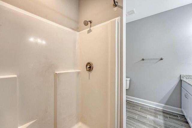 full bathroom featuring wood finish floors, vanity, visible vents, a shower, and toilet